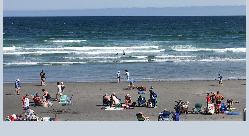 People enjoying Long Sands Beach in front of Sea Spray Cottages